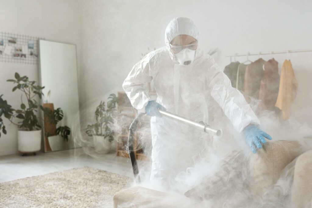 A person in protective suit disinfecting a room to eliminate viruses and bacteria.
